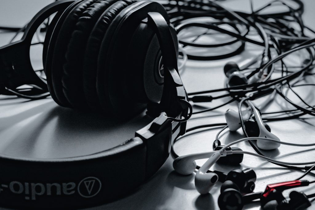 A photo of several pairs of headphones tangled across a white surface.