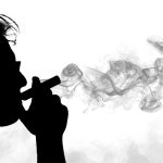 A black & white image of a man holding a vape to his mouth. Vapour fills most of the frame.